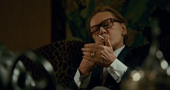 Movie still from “Saint Laurent” (2014), directed by Bertrand Bonello – An older man smoking a cigarette while sitting in a chair; Close Up shot, Low angle