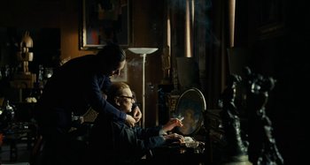 Movie still from “Saint Laurent” (2014), directed by Bertrand Bonello – A man sitting at a table with a woman; Medium shot, Over the shoulder angle