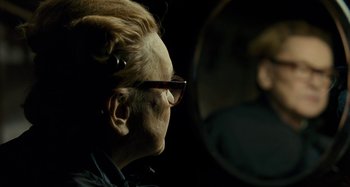 Movie still from “Saint Laurent” (2014), directed by Bertrand Bonello – An older woman looking in the mirror with glasses on; Close Up shot, Over the shoulder angle