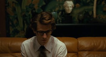 Movie still from “Saint Laurent” (2014), directed by Bertrand Bonello – A man sitting on top of a couch wearing a tie; Close Up shot, Over the shoulder angle