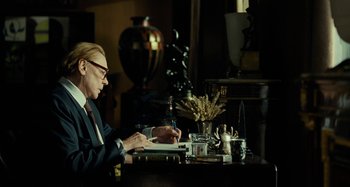 Movie still from “Saint Laurent” (2014), directed by Bertrand Bonello – A man sitting at a table writing on a piece of paper; Medium shot, Over the shoulder angle