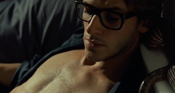 Movie still from “Saint Laurent” (2014), directed by Bertrand Bonello – A person wearing glasses and a black shirt; Close Up shot, High angle