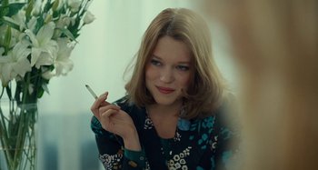 Movie still from “Saint Laurent” (2014), directed by Bertrand Bonello – A woman holding a cigarette in her hand; Close Up shot, Over the shoulder angle