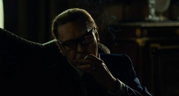 Movie still from “Saint Laurent” (2014), directed by Bertrand Bonello – A man smoking a cigarette while sitting in a dark room; Close Up shot, Low angle