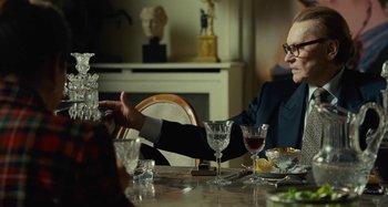 Movie still from “Saint Laurent” (2014), directed by Bertrand Bonello – Two people sitting at a dinner table talking to each other; Medium shot, Over the shoulder angle