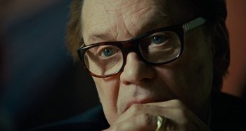 Movie still from “Saint Laurent” (2014), directed by Bertrand Bonello – An older man wearing glasses and a gold ring; Close Up shot, Over the shoulder angle