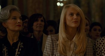 Movie still from “Saint Laurent” (2014), directed by Bertrand Bonello – A woman in a checkered jacket is looking up at something; Close Up shot, Over the shoulder angle