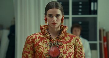 Movie still from “Saint Laurent” (2014), directed by Bertrand Bonello – A woman in a red and gold dress with a necklace; Close Up shot, Over the shoulder angle