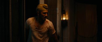 Movie still from “Sardar Udham” (2021), directed by Shoojit Sircar – A man with a turban on his head is standing in front of a window; Medium shot, Over the shoulder angle