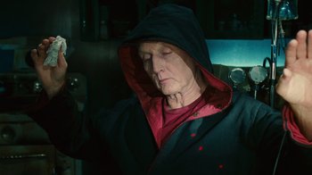 Movie still from “Saw II” (2005), directed by Darren Lynn Bousman – An older woman wearing a black hooded jacket; Close Up shot, Low angle
