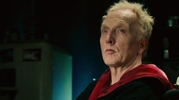 Movie still from “Saw II” (2005), directed by Darren Lynn Bousman – An older man with blonde spiky hair wearing a black shirt; Close Up shot, Low angle