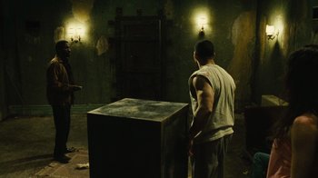 Movie still from “Saw II” (2005), directed by Darren Lynn Bousman – A man standing next to a box in a room; Wide shot, High angle