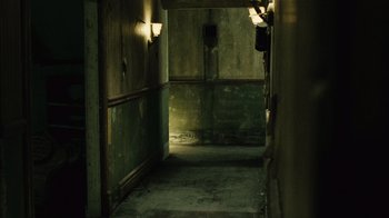 Movie still from “Saw II” (2005), directed by Darren Lynn Bousman – An empty room with a green wall and a light on the wall; Wide shot, High angle