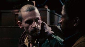 Movie still from “Saw II” (2005), directed by Darren Lynn Bousman – A man with a goatee is talking to another man; Close Up shot, Over the shoulder angle