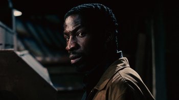 Movie still from “Saw II” (2005), directed by Darren Lynn Bousman – A person wearing a brown jacket; Close Up shot, Over the shoulder angle