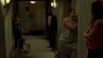 Movie still from “Saw II” (2005), directed by Darren Lynn Bousman – A group of men standing next to each other in a room; Wide shot, High angle