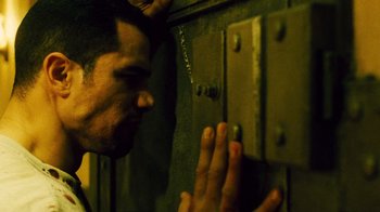 Movie still from “Saw II” (2005), directed by Darren Lynn Bousman – A man with his hands clasped in front of a wall; Close Up shot, Low angle