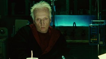 Movie still from “Saw II” (2005), directed by Darren Lynn Bousman – An older man sitting in front of a lit candle; Medium shot, Low angle