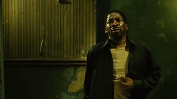 Movie still from “Saw II” (2005), directed by Darren Lynn Bousman – A man standing in front of a wall holding a cigarette in his mouth; Close Up shot, Low angle