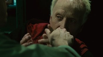 Movie still from “Saw II” (2005), directed by Darren Lynn Bousman – An older man is holding his hands up to his face; Close Up shot, High angle