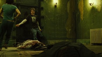 Movie still from “Saw II” (2005), directed by Darren Lynn Bousman – A man standing on a bed in front of a green wall; Wide shot, Low angle