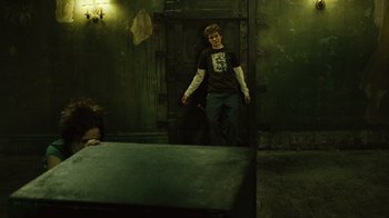 Movie still from “Saw II” (2005), directed by Darren Lynn Bousman – A young man standing in front of an old door; Wide shot, Over the shoulder angle