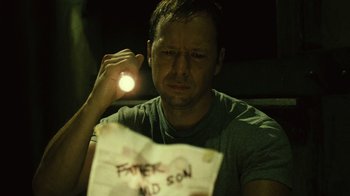 Movie still from “Saw II” (2005), directed by Darren Lynn Bousman – A man holding a flashlight over his head; Close Up shot, High angle