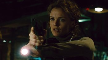 Movie still from “Saw II” (2005), directed by Darren Lynn Bousman – A woman is holding a gun in a dark room; Close Up shot, Low angle