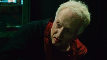 Movie still from “Saw II” (2005), directed by Darren Lynn Bousman – An older man with white hair and a red shirt; Close Up shot, High angle