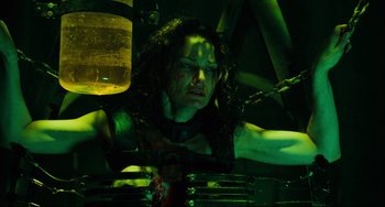 Movie still from “Saw III” (2006), directed by Darren Lynn Bousman – A woman in a black shirt is in a green room; Medium shot, Low angle