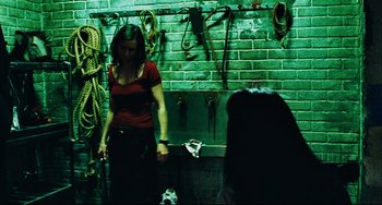 Movie still from “Saw III” (2006), directed by Darren Lynn Bousman – A woman standing in front of a brick wall holding a dog; Medium shot, Over the shoulder angle
