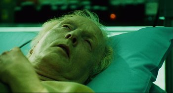Movie still from “Saw III” (2006), directed by Darren Lynn Bousman – An older man laying in a bed with a green blanket; Close Up shot, Low angle