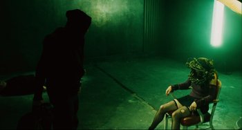 Movie still from “Saw III” (2006), directed by Darren Lynn Bousman – A person sitting on a chair in a dark room; Wide shot, Over the shoulder angle