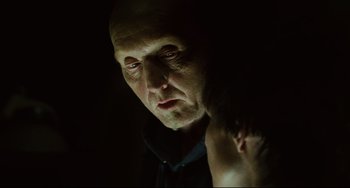 Movie still from “Saw III” (2006), directed by Darren Lynn Bousman – An older man looking into a mirror in a dark room; Close Up shot, Over the shoulder angle