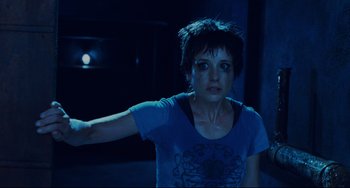 Movie still from “Saw III” (2006), directed by Darren Lynn Bousman – A woman with short hair is standing in a dark room; Close Up shot, Over the shoulder angle
