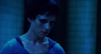 Movie still from “Saw III” (2006), directed by Darren Lynn Bousman – A woman with short black hair is looking at the camera; Close Up shot, Low angle