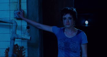 Movie still from “Saw III” (2006), directed by Darren Lynn Bousman – A woman standing in front of a wall with her arm outstreched; Medium shot, High angle