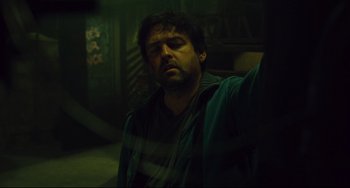 Movie still from “Saw III” (2006), directed by Darren Lynn Bousman – A man in a dark room with his eyes wide open; Medium shot, Low angle