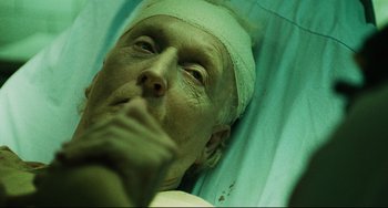 Movie still from “Saw III” (2006), directed by Darren Lynn Bousman – An old man with bandages on his head is laying in a hospital bed; Close Up shot, Overhead angle