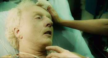 Movie still from “Saw III” (2006), directed by Darren Lynn Bousman – An older man is getting his head shaved by an older woman; Close Up shot, Overhead angle