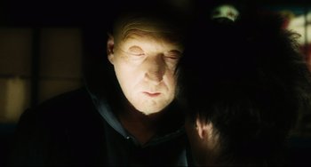 Movie still from “Saw III” (2006), directed by Darren Lynn Bousman – A man with his eyes closed in a dark room; Close Up shot, Over the shoulder angle
