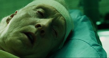 Movie still from “Saw III” (2006), directed by Darren Lynn Bousman – An old woman with a bandaged head lying on a hospital bed; Close Up shot, Overhead angle