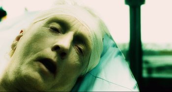 Movie still from “Saw III” (2006), directed by Darren Lynn Bousman – A man with a bandaged head laying in a hospital bed; Close Up shot, Overhead angle