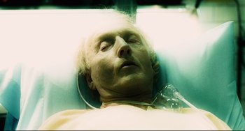Movie still from “Saw III” (2006), directed by Darren Lynn Bousman – An old man laying in a hospital bed with his eyes closed; Close Up shot, High angle