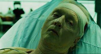 Movie still from “Saw III” (2006), directed by Darren Lynn Bousman – A man with a bandage on his head is laying in a hospital bed; Close Up shot, Low angle