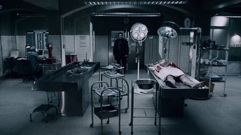 Movie still from “Saw IV” (2007), directed by Darren Lynn Bousman – A man standing in front of an autopsy table; Wide shot, High angle