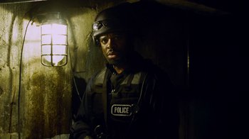 Movie still from “Saw IV” (2007), directed by Darren Lynn Bousman – A man in a police uniform standing next to a window; Close Up shot, Low angle
