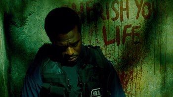 Movie still from “Saw IV” (2007), directed by Darren Lynn Bousman – A police officer is standing in front of a wall; Close Up shot, High angle