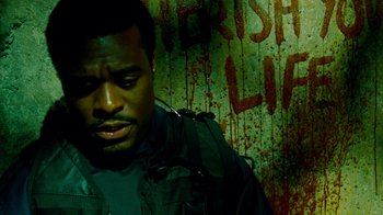 Movie still from “Saw IV” (2007), directed by Darren Lynn Bousman – A man in a green jacket standing in front of a wall; Close Up shot, High angle