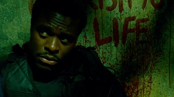 Movie still from “Saw IV” (2007), directed by Darren Lynn Bousman – A man in a black jacket is in front of a wall; Close Up shot, Low angle